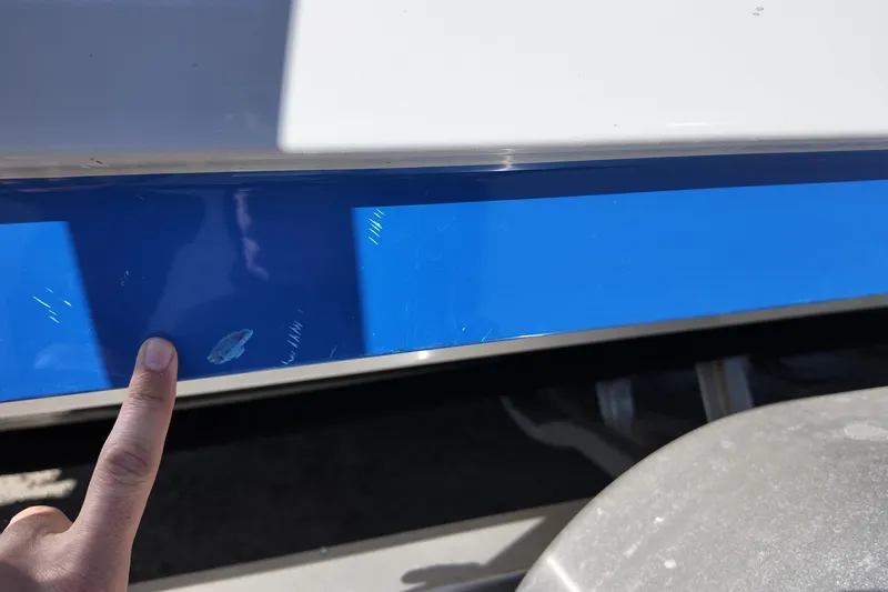 Slide: The Image of 2024 Yamaha Boats 275SE with minor hull damage, finger pointing at scratch. - 21