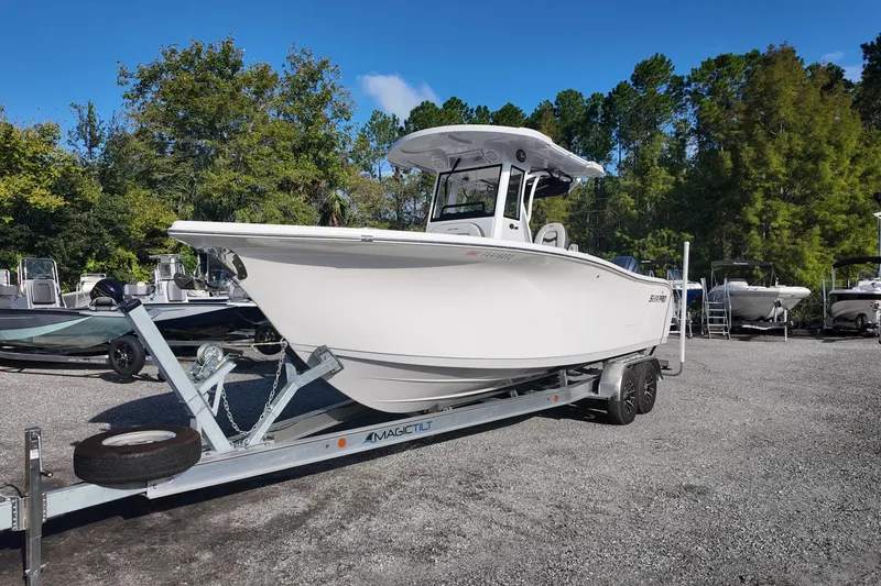Slide: The Image of 2025 Sea Pro 262 Offshore boat on trailer, surrounded by trees and other boats. - 2