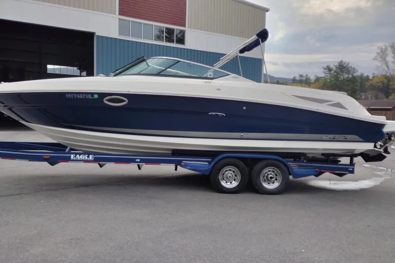 The Image of 2013 Sea Ray 300 SLX boat on trailer, parked outside a warehouse. - 0