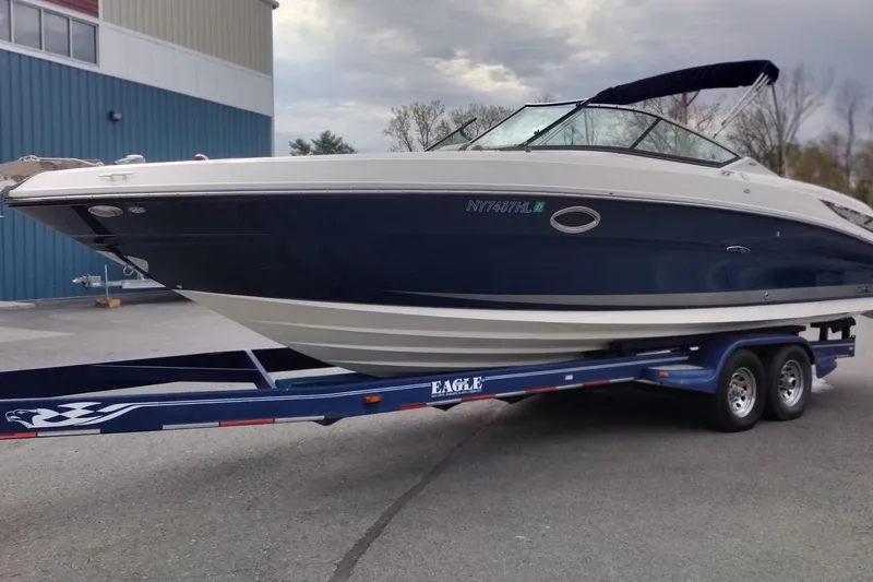 Slide: The Image of 2013 Sea Ray 300 SLX boat on trailer, parked outdoors near a blue building. - 1