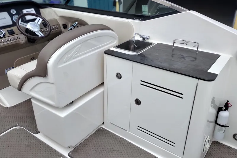 Slide: The Image of 2013 Sea Ray 300 SLX boat interior with helm, sink, and storage cabinet. - 16
