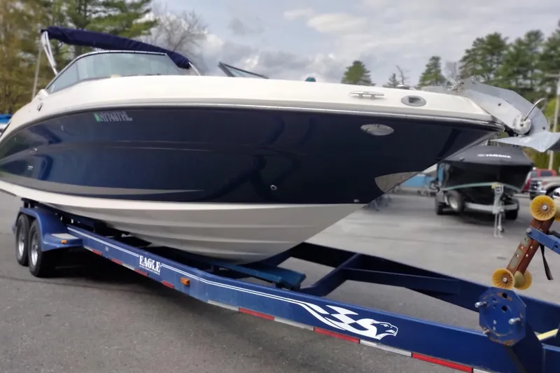 Slide: The Image of 2013 Sea Ray 300 SLX boat on a trailer, parked outdoors with trees in the background. - 2