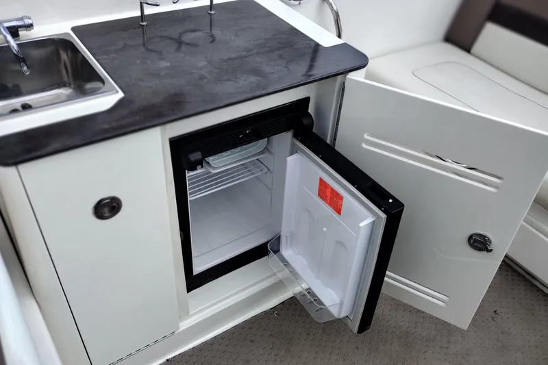 Slide: The Image of 2013 Sea Ray 300 SLX boat kitchenette with open mini fridge and sink. - 27