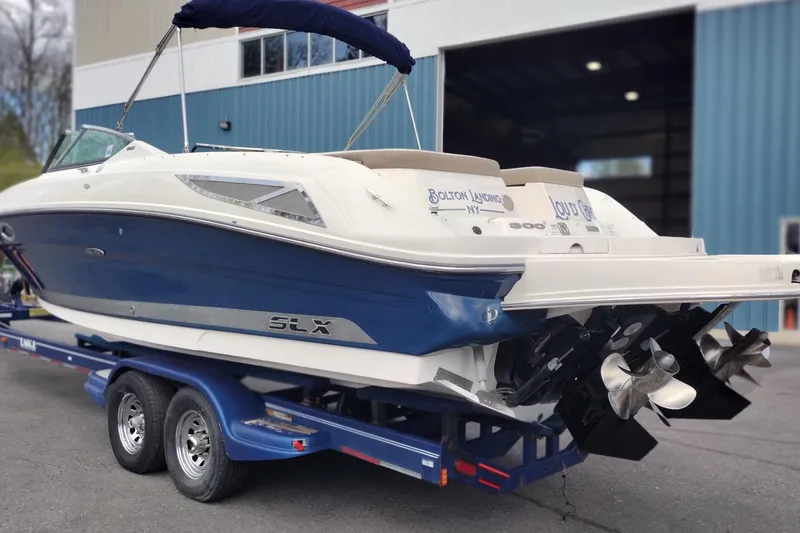 Slide: The Image of 2013 Sea Ray 300 SLX boat on trailer, blue and white exterior, docked near a building. - 5