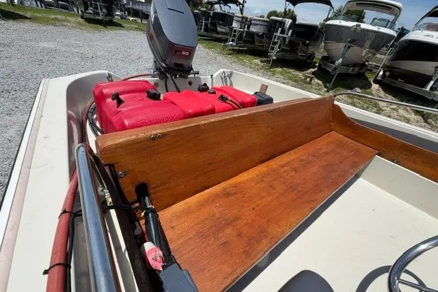 Slide: The Image of 1984 Boston Whaler 150 Sport boat interior with wooden seating and red fuel tanks. - 12