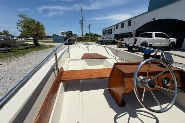 Slide: The Image of 1984 Boston Whaler 150 Sport boat with wooden accents, parked outdoors. - 16