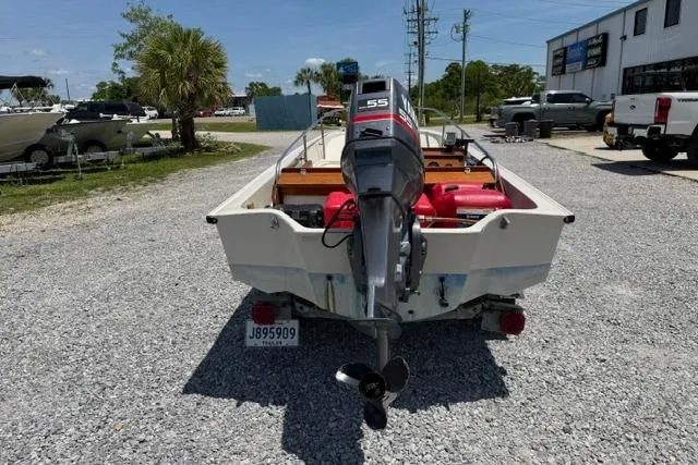 Slide: The Image of 1984 Boston Whaler 150 Sport boat with outboard motor, parked on gravel lot. - 3