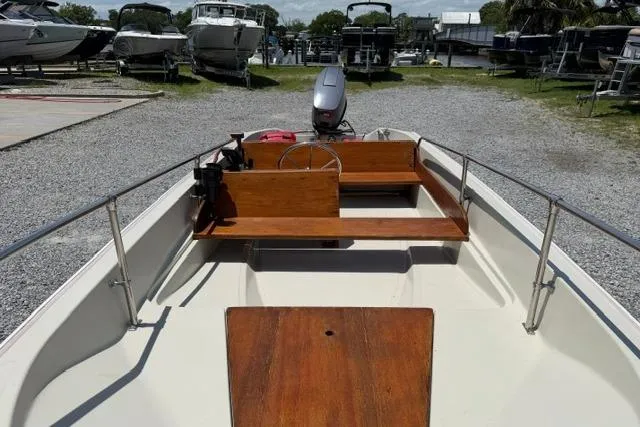 Slide: The Image of 1984 Boston Whaler 150 Sport boat with wooden interior, parked on gravel near other boats. - 9