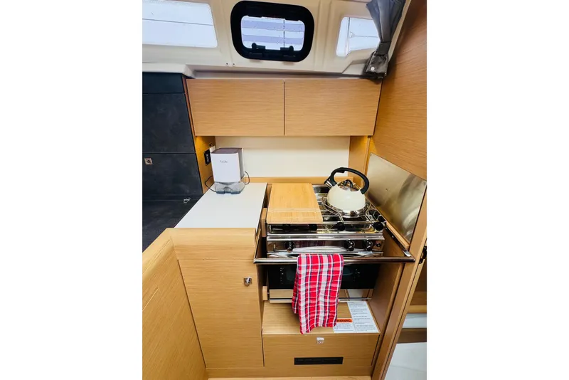 Slide: The Image of 2024 Jeanneau Sun Odyssey 349 yacht kitchen with stove, kettle, and wooden cabinetry. - 44