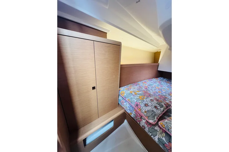 Slide: The Image of 2024 Jeanneau Sun Odyssey 349 cabin interior with floral bedding and wooden cabinetry. - 60