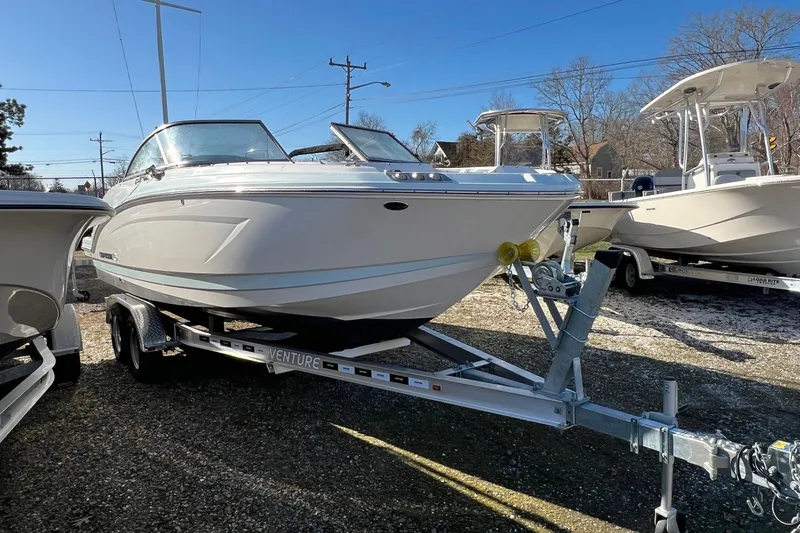 Slide: The Image of 2021 Chaparral 230 Suncoast boat on trailer, displayed outdoors under clear blue sky. - 3