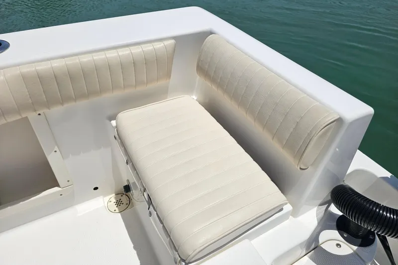 Slide: The Image of 2005 Mako 212 Center Console boat interior with cushioned seating, near water. - 37