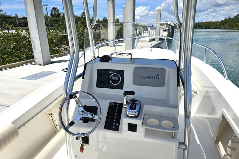 Slide: The Image of 2005 Mako 212 Center Console boat with Garmin navigation, docked by a scenic waterway. - 38
