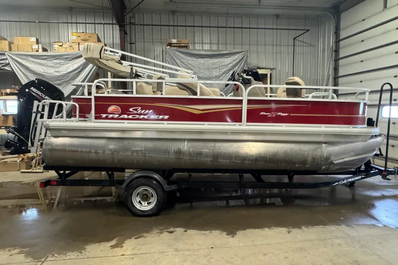 The Image of 2022 Sun Tracker Bass Buggy 18 DLX pontoon boat in a garage setting. - 0