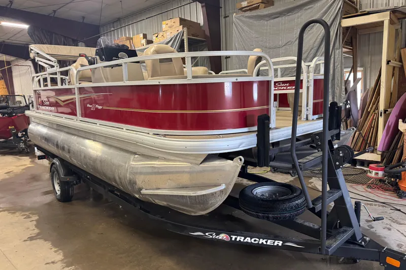 Slide: The Image of 2022 Sun Tracker Bass Buggy 18 DLX pontoon boat on trailer in a garage. - 2