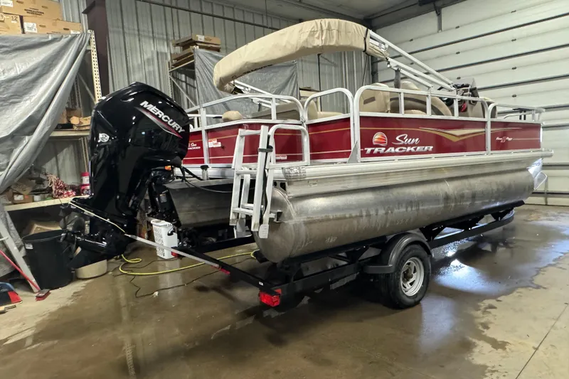 Slide: The Image of 2022 Sun Tracker Bass Buggy 18 DLX pontoon boat in a garage setting. - 3