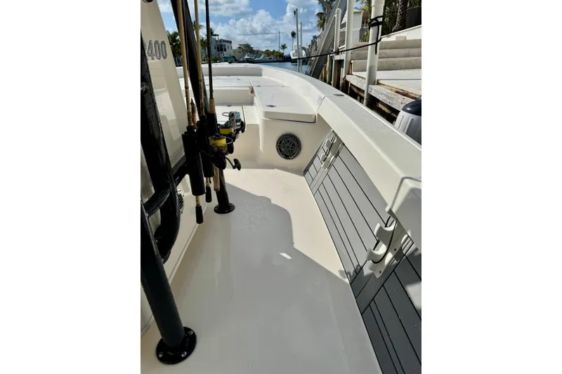 Slide: The Image of 2021 Pathfinder 2400 TRS boat interior with fishing rods and seating, docked under sunny skies. - 6