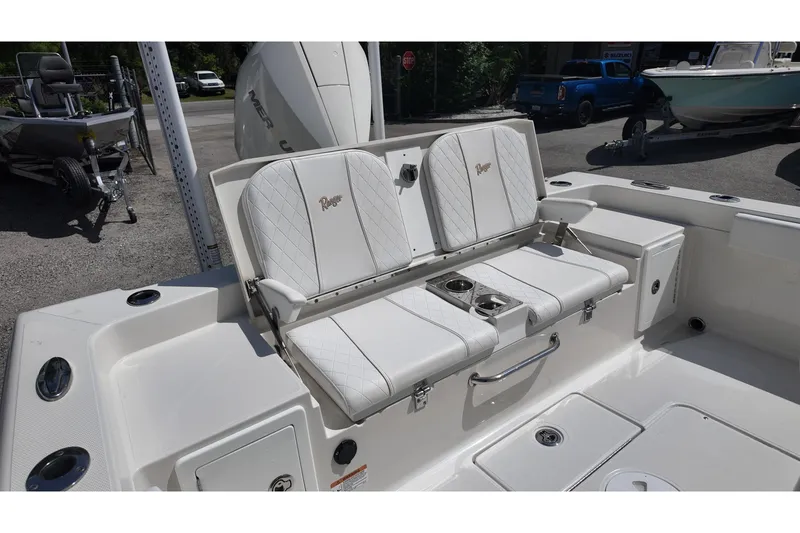 Slide: The Image of 2024 Ranger 2660 Bay boat with white cushioned seating and cup holders. - 13