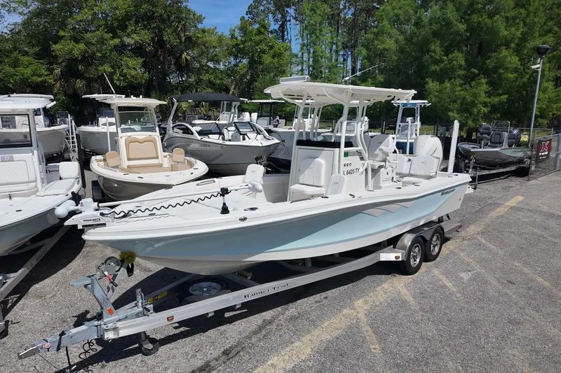 Slide: The Image of 2024 Ranger 2660 Bay boat on trailer, surrounded by other boats, in a parking area. - 2