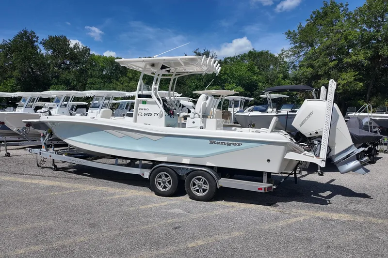 Slide: The Image of 2024 Ranger 2660 Bay boat on trailer, parked outdoors under a clear blue sky. - 3