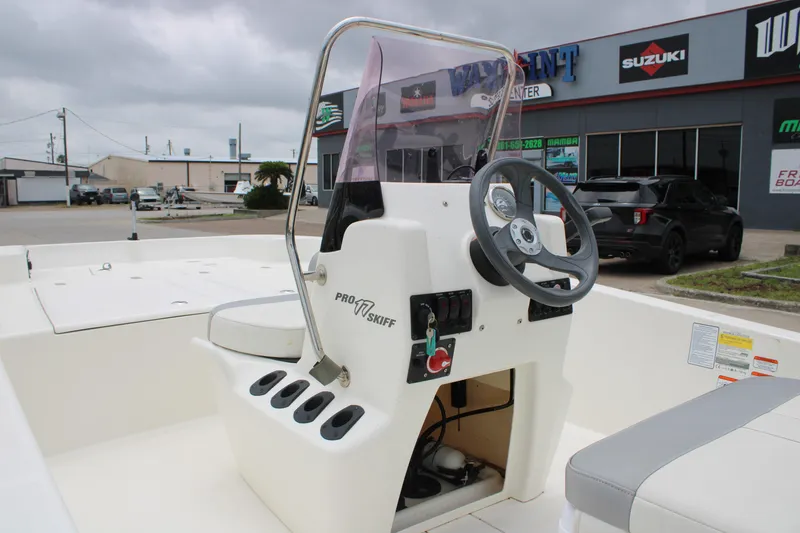 Slide: The Image of 2021 Mako Pro Skiff 17 CC boat console with steering wheel and controls, parked outdoors. - 13