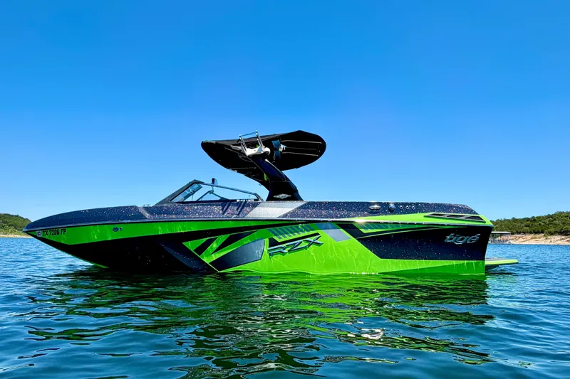 The Image of 2016 Tigé RZX3 boat in vibrant green and black on a sunny lake. - 1