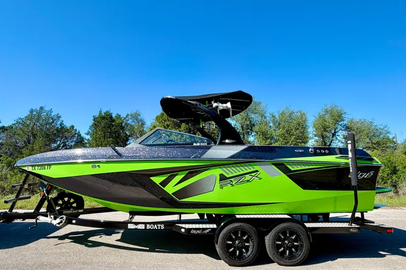 Slide: The Image of 2016 Tigé RZX3 boat in vibrant green and black on a trailer, under clear blue sky. - 10