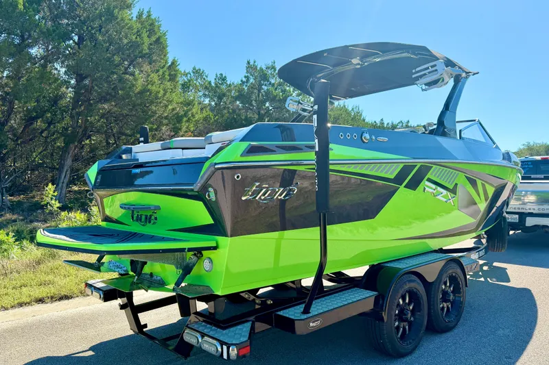 Slide: The Image of 2016 Tigé RZX3 boat in vibrant green on a trailer, parked on a sunny road. - 11