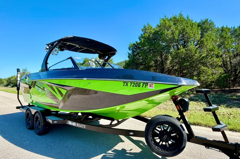 Slide: The Image of 2016 Tigé RZX3 boat in vibrant green on a trailer, parked on a sunny road. - 12