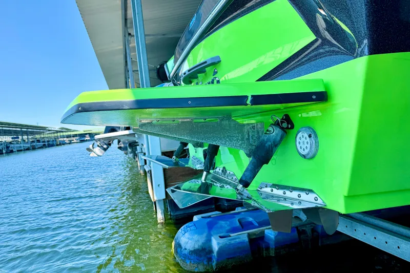 Slide: The Image of 2016 Tigé RZX3 boat docked, vibrant green hull, detailed view of stern and water. - 13
