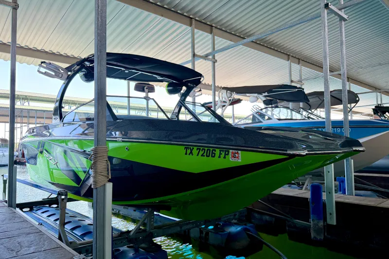 Slide: The Image of 2016 Tigé RZX3 boat in vibrant green, docked under a covered marina. - 14