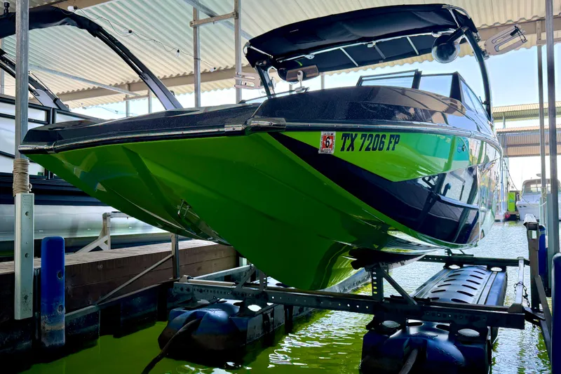 Slide: The Image of 2016 Tigé RZX3 boat in vibrant green, docked on a lift in a marina. - 16