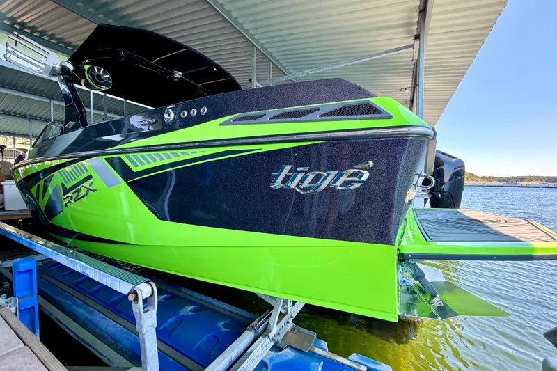 Slide: The Image of 2016 Tigé RZX3 boat in vibrant green and black, docked at a marina. - 17