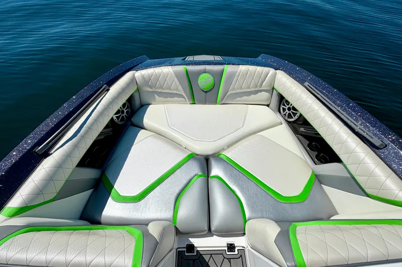 Slide: The Image of 2016 Tigé RZX3 boat interior with white and green seating on calm water. - 33