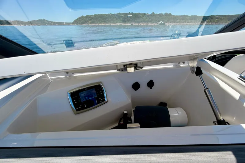 Slide: The Image of 2016 Tigé RZX3 boat storage compartment with control panel, open hatch, and scenic water view. - 39