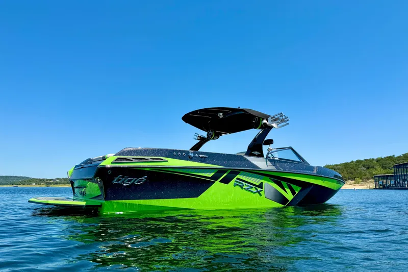 Slide: The Image of 2016 Tigé RZX3 boat with vibrant green and black design on a sunny lake. - 6