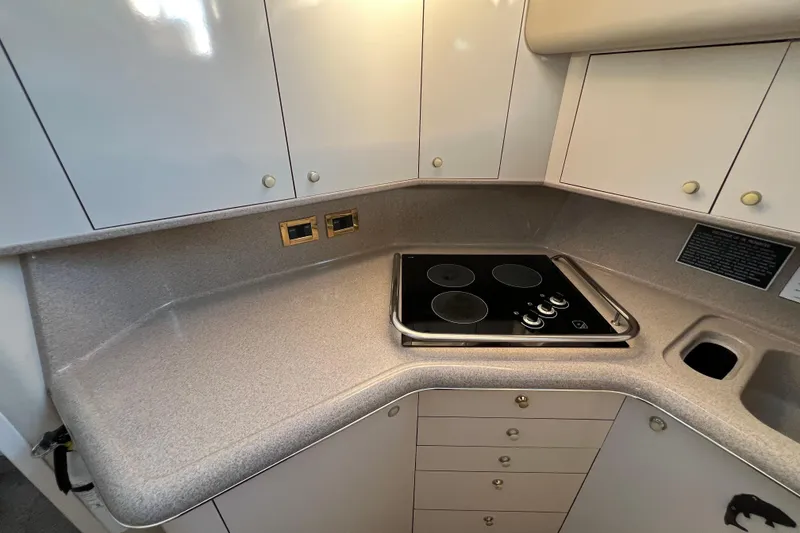 Slide: The Image of 1997 Sea Ray 370 Aft Cabin kitchen with stovetop and sleek cabinetry. - 38