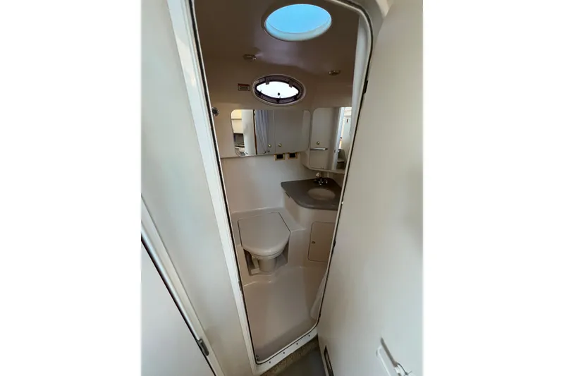 Slide: The Image of 1997 Sea Ray 370 Aft Cabin bathroom with sink, toilet, and porthole window. - 54