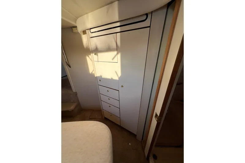 Slide: The Image of 1997 Sea Ray 370 Aft Cabin interior with built-in storage and soft lighting. - 70