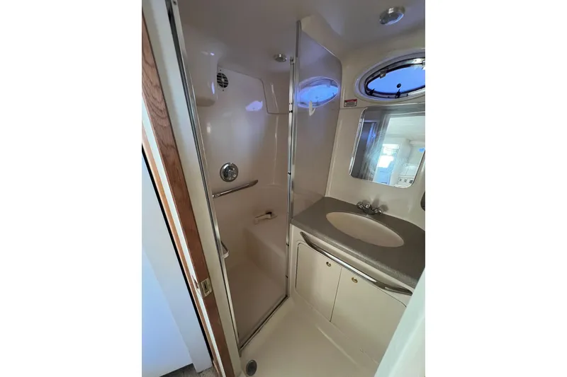 Slide: The Image of 1997 Sea Ray 370 Aft Cabin bathroom with shower, sink, and porthole window. - 73