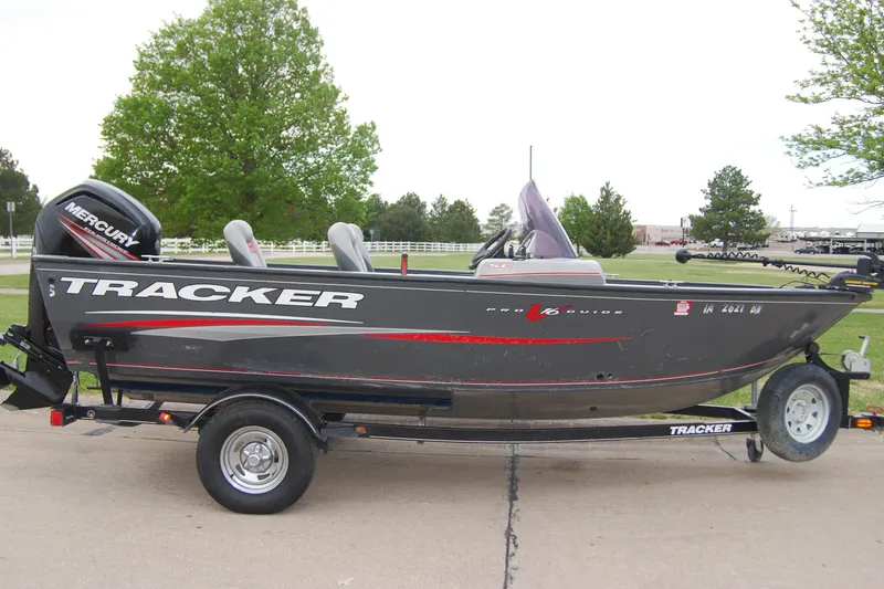 The Image of 2015 Tracker Pro Guide V-16 SC fishing boat on trailer, parked outdoors. - 0