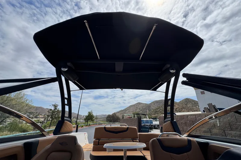 Slide: The Image of 2024 Chaparral 247 SSX boat interior with canopy, showcasing luxury seating and scenic mountain backdrop. - 22
