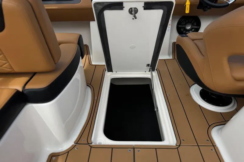 Slide: The Image of 2024 Chaparral 247 SSX boat interior with open storage compartment and tan seating. - 30
