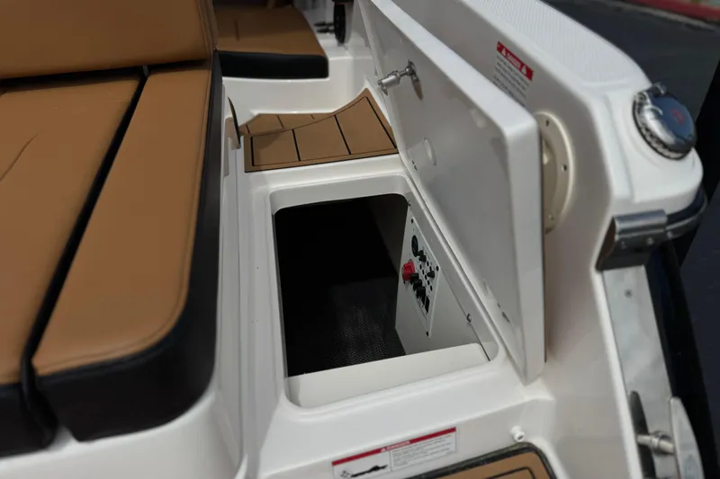 Slide: The Image of 2024 Chaparral 247 SSX boat storage compartment with tan seating and open hatch. - 9