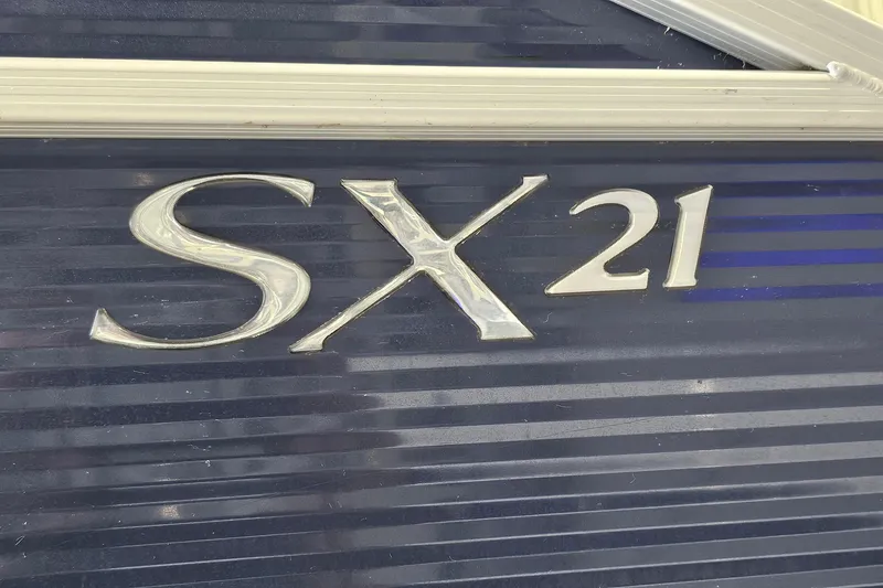 Slide: The Image of Close-up of 2019 Bennington 21 SX SWINGBACK model emblem on dark background. - 21