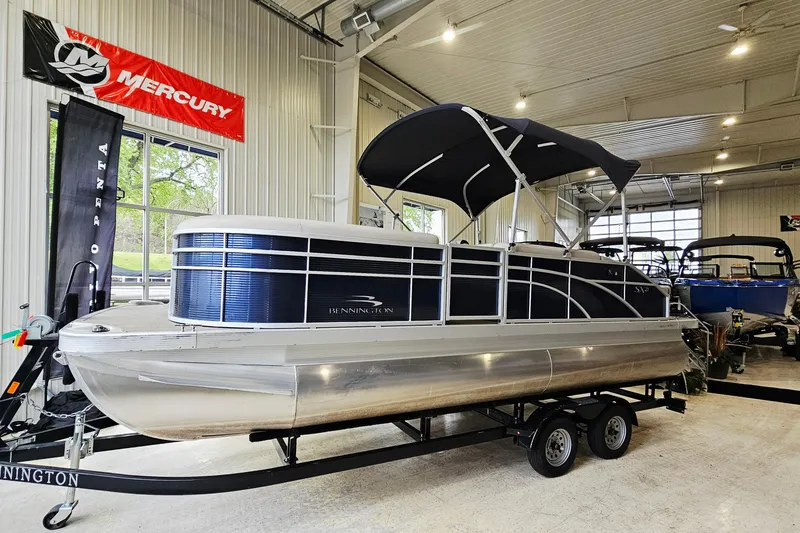 Slide: The Image of 2019 Bennington 21 SX Swingback pontoon boat displayed indoors on a trailer. - 4