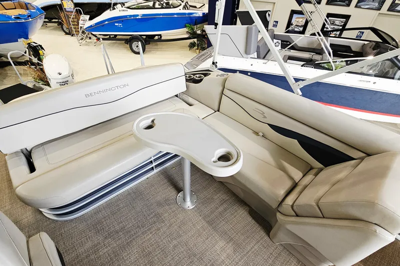 Slide: The Image of 2019 Bennington 21 SX Swingback boat interior with beige seating and table in showroom. - 8