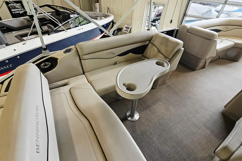 Slide: The Image of 2019 Bennington 21 SX Swingback boat interior with beige seating and cupholder table. - 9