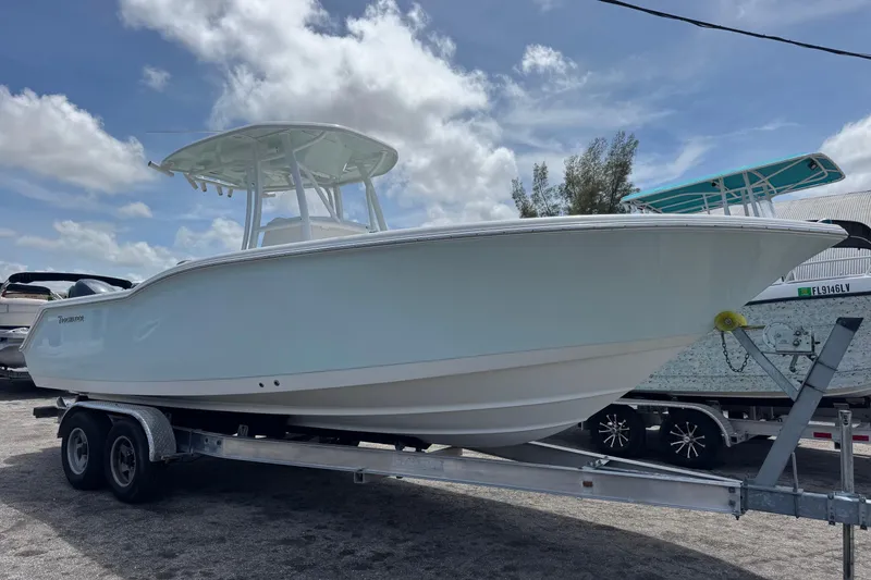 The Image of 2014 Tidewater 250 CC Adventure boat on trailer under cloudy sky. - 1