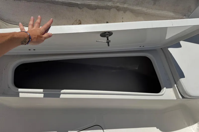 Slide: The Image of Open storage compartment on 2014 Tidewater 250 CC Adventure boat, hand lifting lid. - 30